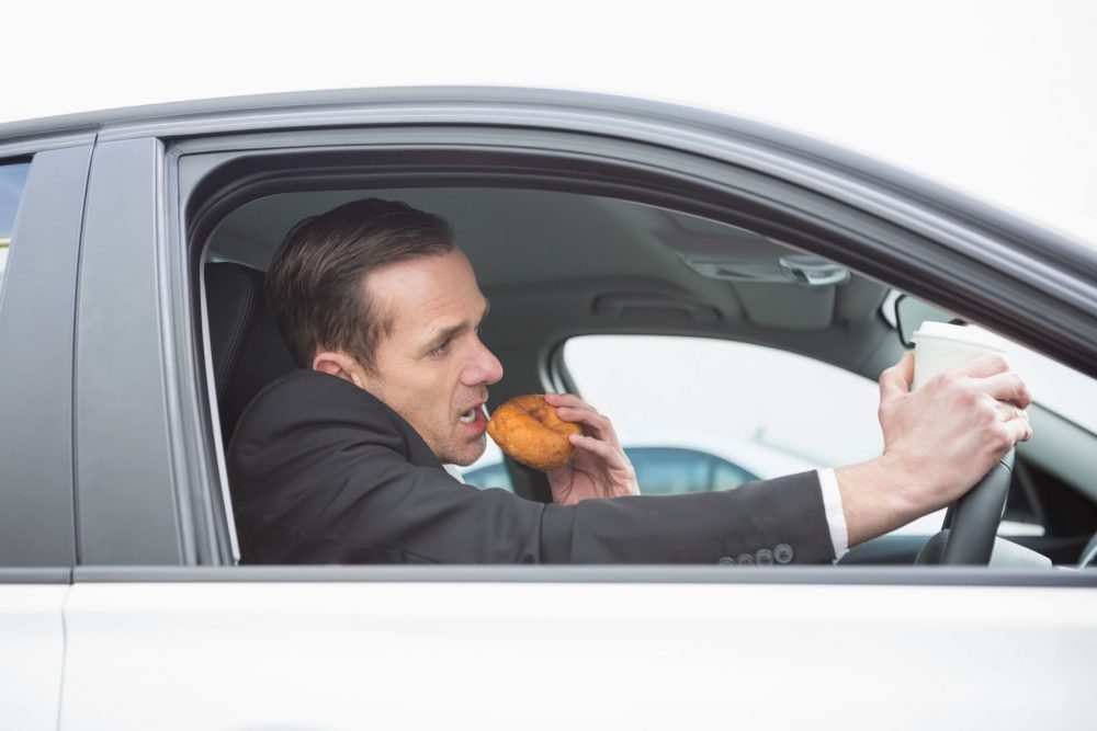 36387097 – businessman having coffee and doughnut on the phone in his car