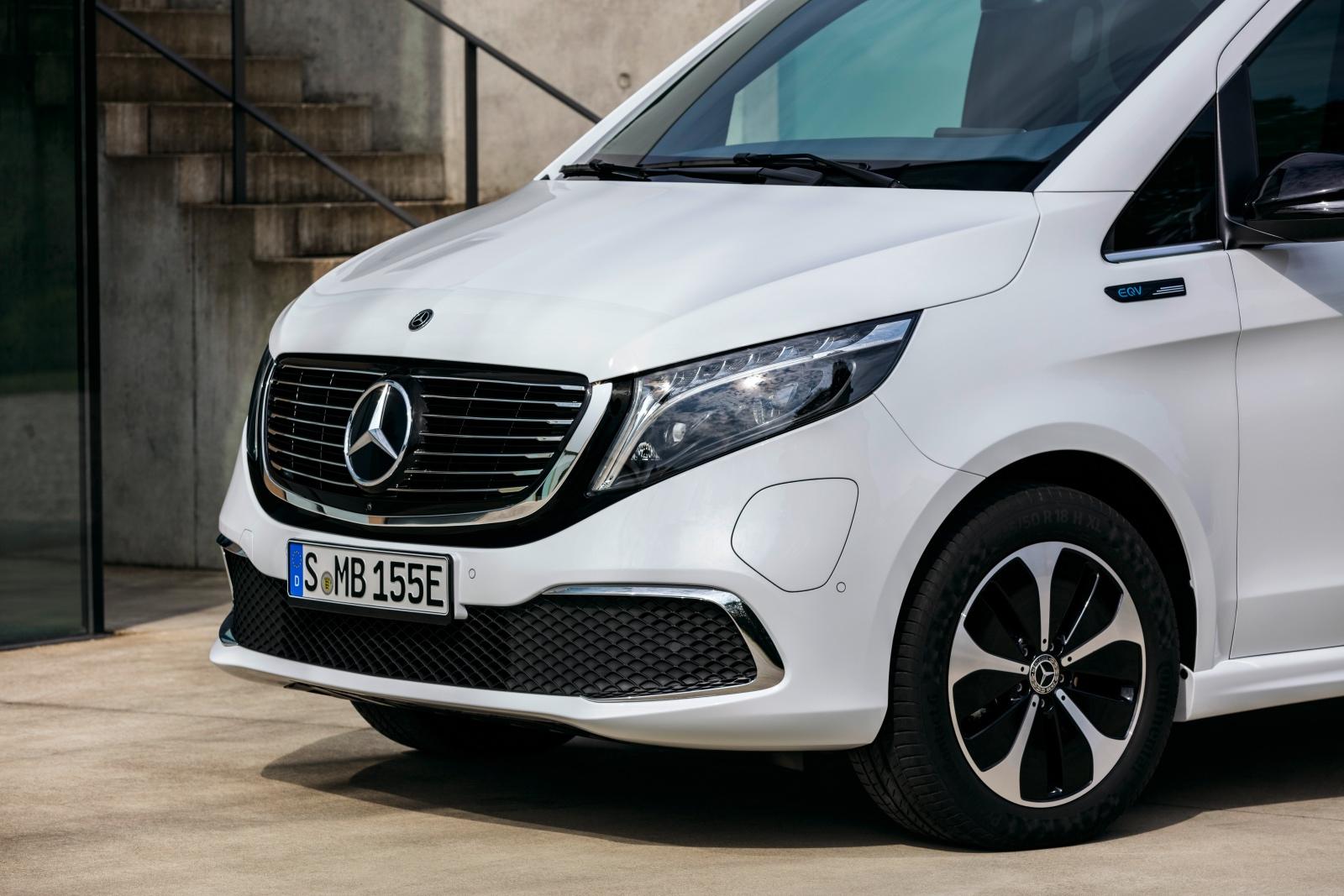Der neue Mercedes-Benz EQV (Stromverbrauch kombiniert: 27,0 kWh/100 km; CO2-Emissionen kombiniert: 0 g/km, Angaben vorläufig) – Exterieur, Bergkristallweiß metallic, Black Panel-Kühlergrill mit Chromlamellen, Ladeanschluss im Stoßfänger, Seitenansicht mit spezifischen EQ Design-Leichtmetallrädern im 18-Zoll-Format // The new Mercedes-Benz EQV (combined power consumption: 27.0 kWh/100 km; combined CO2 emissions: 0 g/km, provisional figures) – Exterior, Mountain crystal white metallic, black panel radiator grille with chrome fins, charging connection in the bumper, side profile with specific, EQ design, lightweight, 18-inch wheels